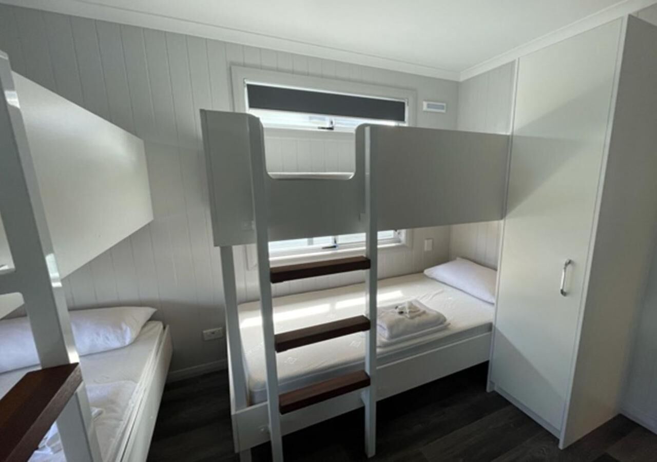 Habitación con literas, ventana, armario y pequeño escritorio.