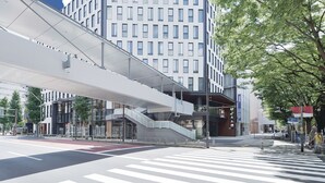 A modern hotel with a prominent entrance, a covered pedestrian walkway, and a clear view of the street.
