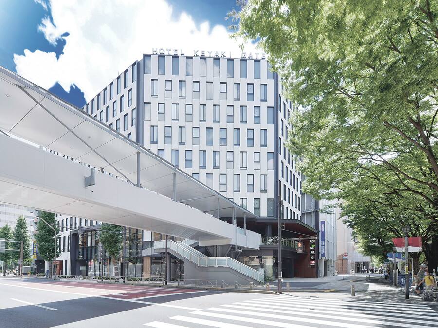 A modern hotel with a prominent entrance, a covered pedestrian walkway, and a clear view of the street.