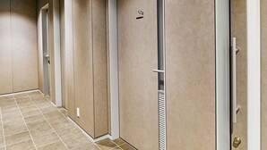 A hallway with doors, a vent, and a smoke alarm.