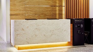 A modern reception desk with a marble top and a wooden panel backdrop.