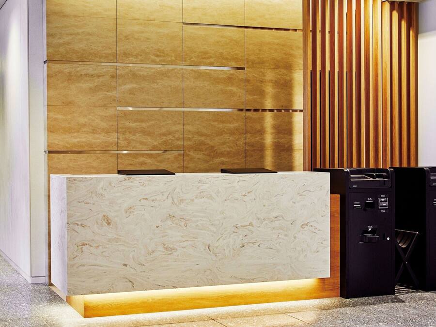 A modern reception desk with a marble top and a wooden panel backdrop.