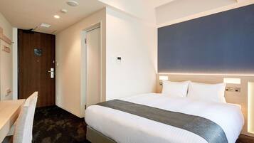 Una camera d'albergo con un letto, un comodino, una sedia e una scrivania.