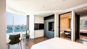A modern hotel room with a large bed, a desk, and a view of a bridge over water. - AG405 Hotel (Busan)
