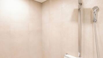 A modern bathroom with a bathtub, a shower with a handheld showerhead, and a wall-mounted control panel.