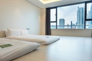 Habitación de hotel con dos camas, un ventanal grande con vista a la ciudad y un diseño moderno.