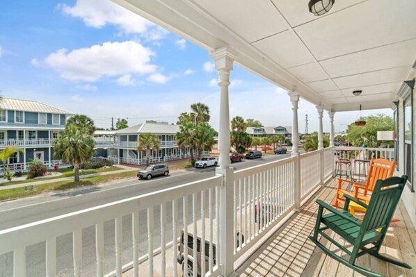 A balcony with a view of a street, palm trees, and buildings.
