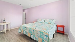 Un dormitorio con cama, mesita de noche, una pequeña mesa y una puerta.