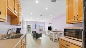 Una cocina moderna con armarios de madera, electrodomésticos de acero inoxidable y un comedor con una silla y una mesa.