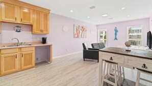 Una cocina moderna con armarios de madera, un lavamanos empotrado y una zona de comedor con mesa y sillas.