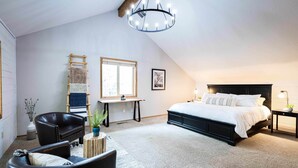 A bedroom with a bed, a desk, a chair, and a chandelier. - Peaceful modern oasis -walking distance to Village (Sunriver)