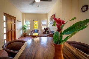 Un coin repas avec une table en bois, des chaises, une plante en pot et une chaise à rayures colorées.