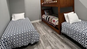 Una habitación con dos camas individuales, una litera, un ventilador de techo y una luz empotrada.