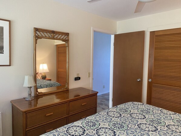 A hotel room with a bed, a dresser, a mirror, a door, and a ceiling fan.