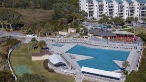 Vista aérea de un resort con una gran piscina central, varias piscinas más pequeñas y un edificio con techo verde.