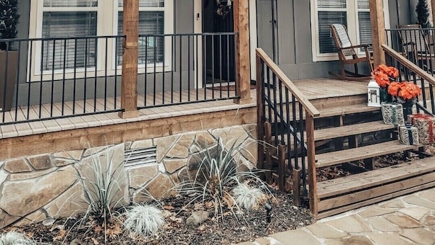 A two-story house with a covered porch, stone foundation, and a wooden staircase leading to the entrance. - Robin’s Nest Cabin- quiet cove on Lake Hamilton (Hot Springs National Park)