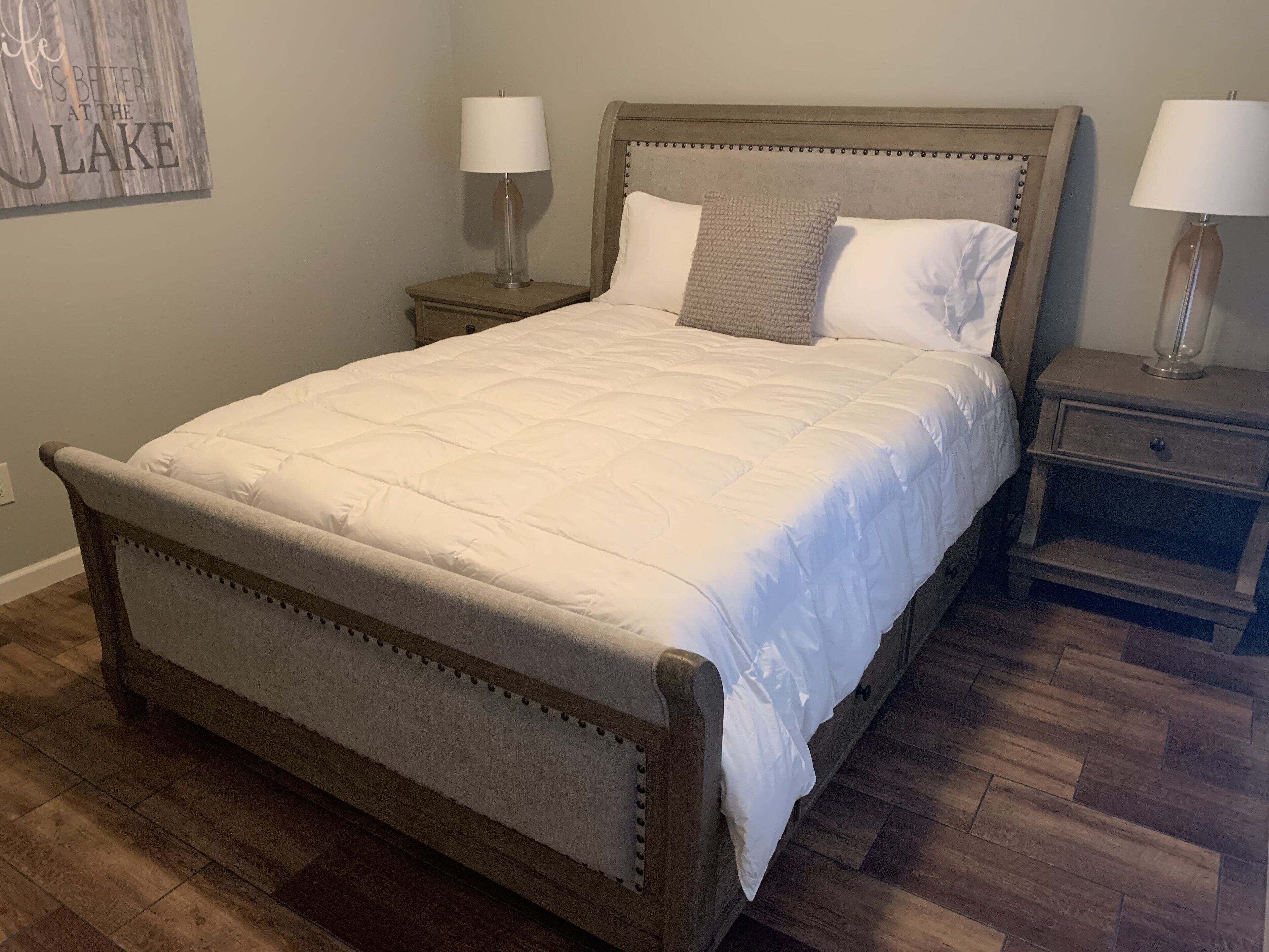 A bedroom with a large bed, two bedside tables, and a wall-mounted lamp.