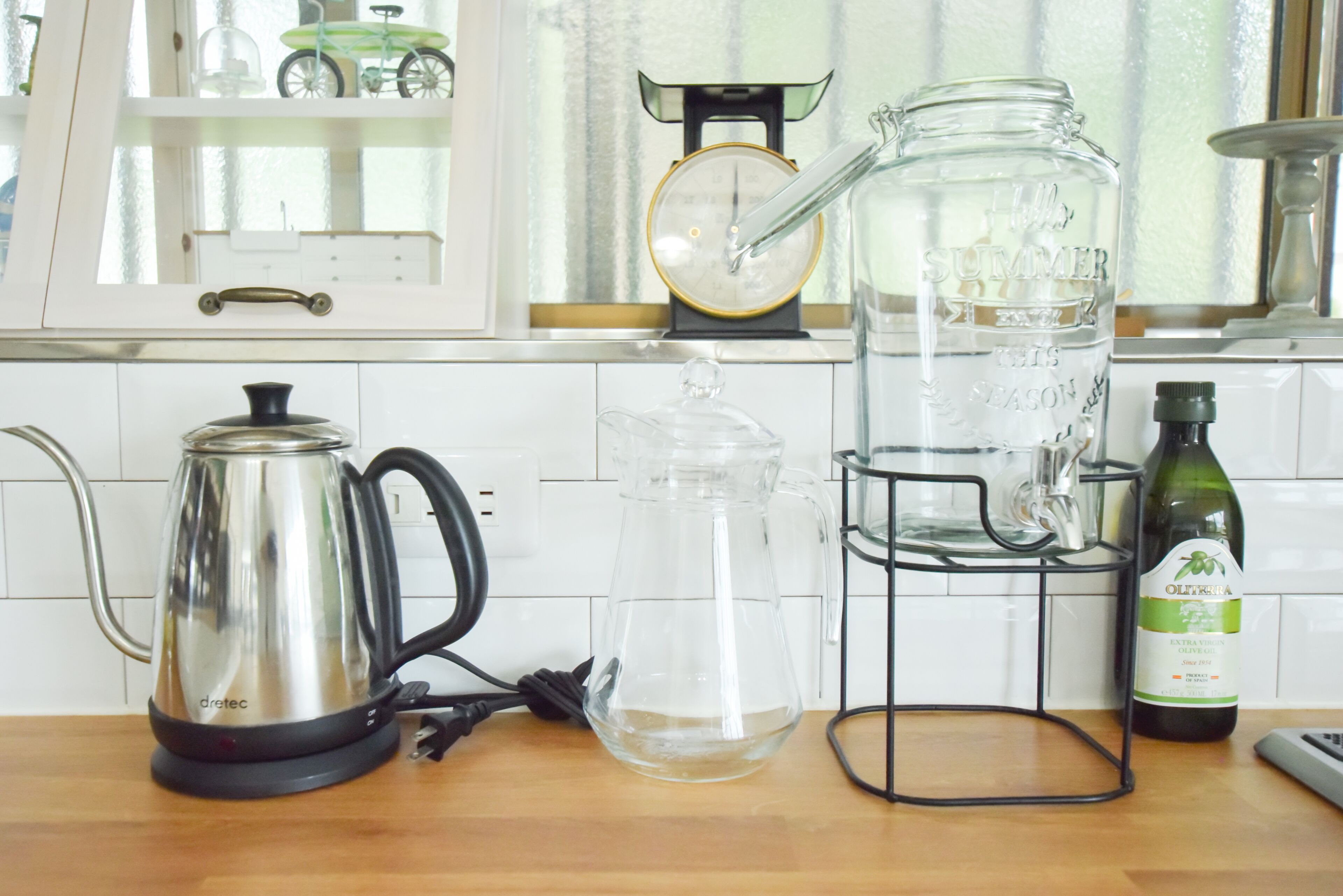 A kitchen with a kettle, a water dispenser, a wine bottle, and a scale.
