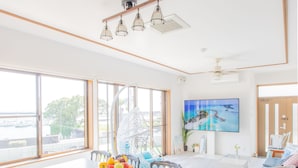 A spacious dining area with a large table and chairs, a ceiling fan, and a large window offering a view of the water. - West coast villa Shirahama (Shirahama)