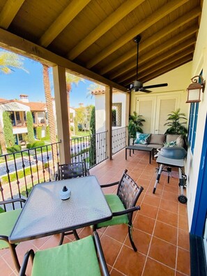 A covered patio with a table and chairs, a ceiling fan, and a view of the neighborhood.