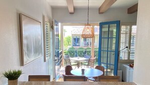 A kitchen with granite countertops, a dining area with a table and chairs, a hanging light fixture, and a view of the outside.