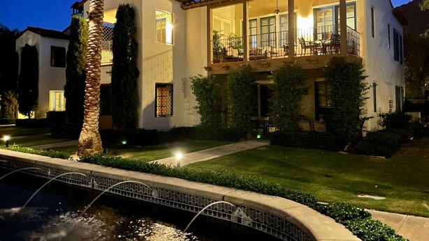 A two-story house with a balcony, a swimming pool, and a well-maintained lawn.