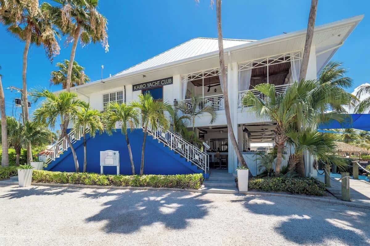 A building with a sign reading "Kaibo Yacht Club" and a staircase leading to the entrance.