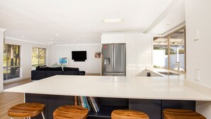 A modern kitchen with a large island, built-in appliances, and a dining area with a sofa and chairs. - Meeseeks - Pet Friendly - 2 Mins Walk to Beach (Culburra Beach)