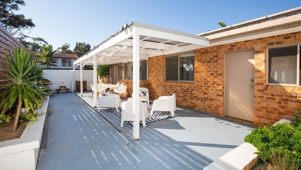 A covered patio area with a white pergola, outdoor seating, and a brick wall. - Meeseeks - Pet Friendly - 2 Mins Walk to Beach (Culburra Beach)