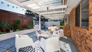 An outdoor patio with white furniture, a patterned rug, and string lights. - Meeseeks - Pet Friendly - 2 Mins Walk to Beach (Culburra Beach)