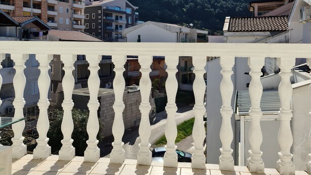 Een balkon met betegelde vloer en een witte balustrade.