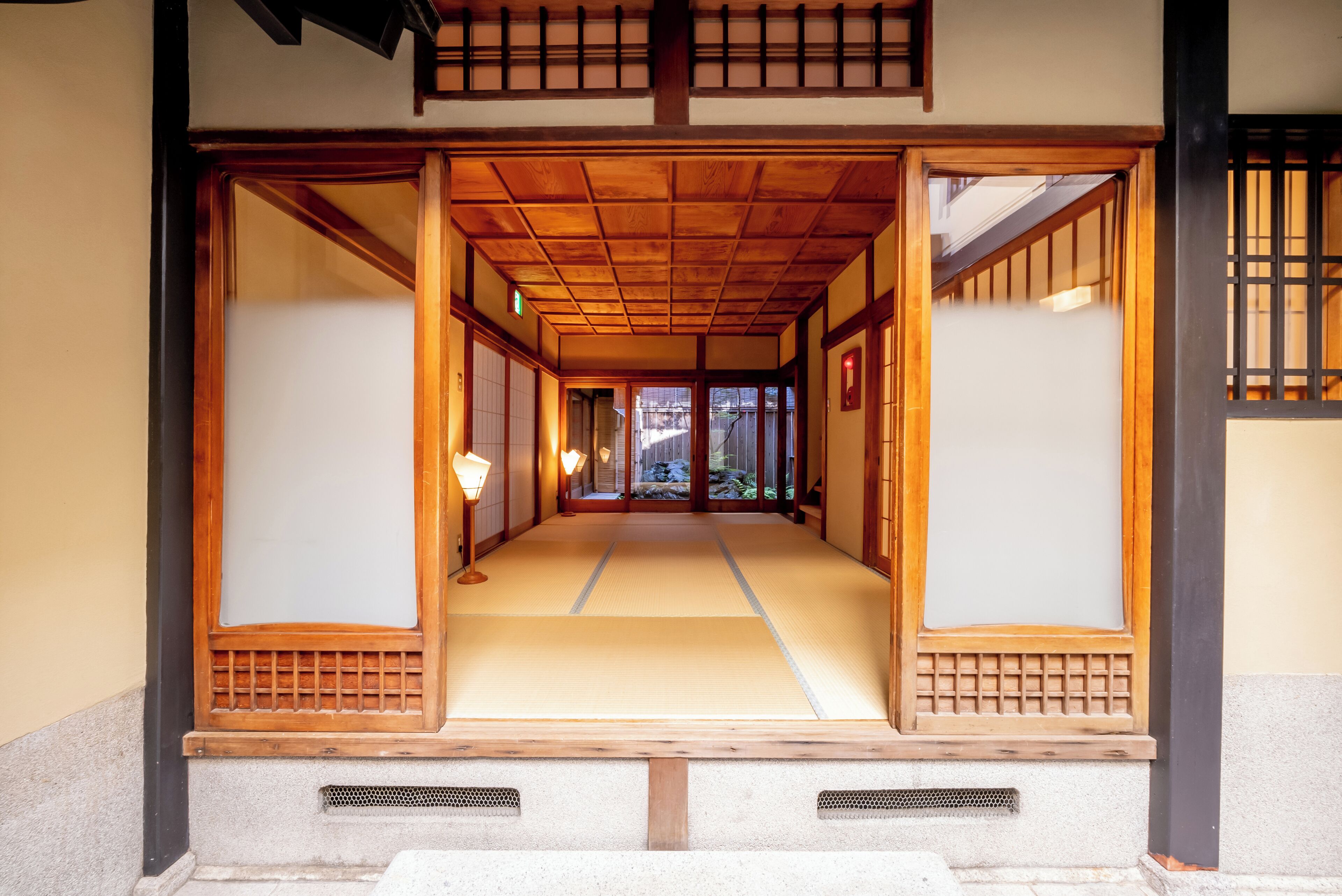 Un interior japonés tradicional con suelo de tatami, puertas correderas de madera y vistas al exterior.