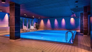 An indoor swimming pool with a tiled floor, a pool ladder, and a few lounge chairs. - Hotel am Stadtpark (Hilden)