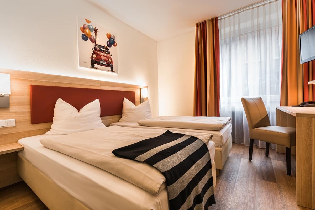 A hotel room with two beds, a desk, and a chair.