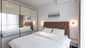 Un dormitorio moderno con una cama grande, un armario con espejo y un aire acondicionado de pared.