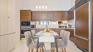 A modern kitchen with wooden cabinets, stainless steel appliances, and a dining table set for four.