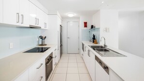 A modern kitchen with white cabinets, a stainless steel sink, and a built-in oven.