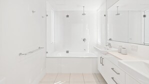 A modern bathroom with a glass-enclosed shower, a freestanding bathtub, and a vanity with a mirror.
