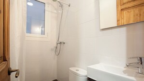 Un baño pequeño y limpio con ducha, inodoro y lavamanos.