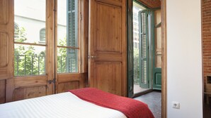 A bedroom with a large wooden door, a window, and a view of the outside. - Family Apartment Near Sagrada Familia (Barcelona)
