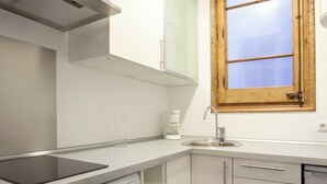 Eine moderne Küche mit integriertem Induktionskochfeld, einer Kaffeemaschine und einem Fenster mit Holzrahmen.