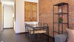 A dining area with a glass table, chairs, and a brick wall. - Bright Apartment Near Sagrada Familia (Barcelona)