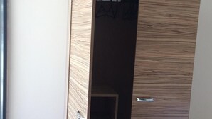 Ein Holzkleiderkasten mit Kleiderstange im Inneren.