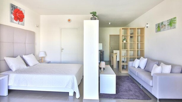Een moderne hotelkamer met een groot bed, een bank, een bureau en een boekenkast.
