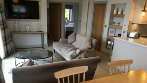 Ein modernes Wohnzimmer mit Sofa, Esstisch und Küchenzeile.
