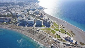 Vue aérienne d’une ville côtière avec une plage, des hôtels et un port de plaisance.