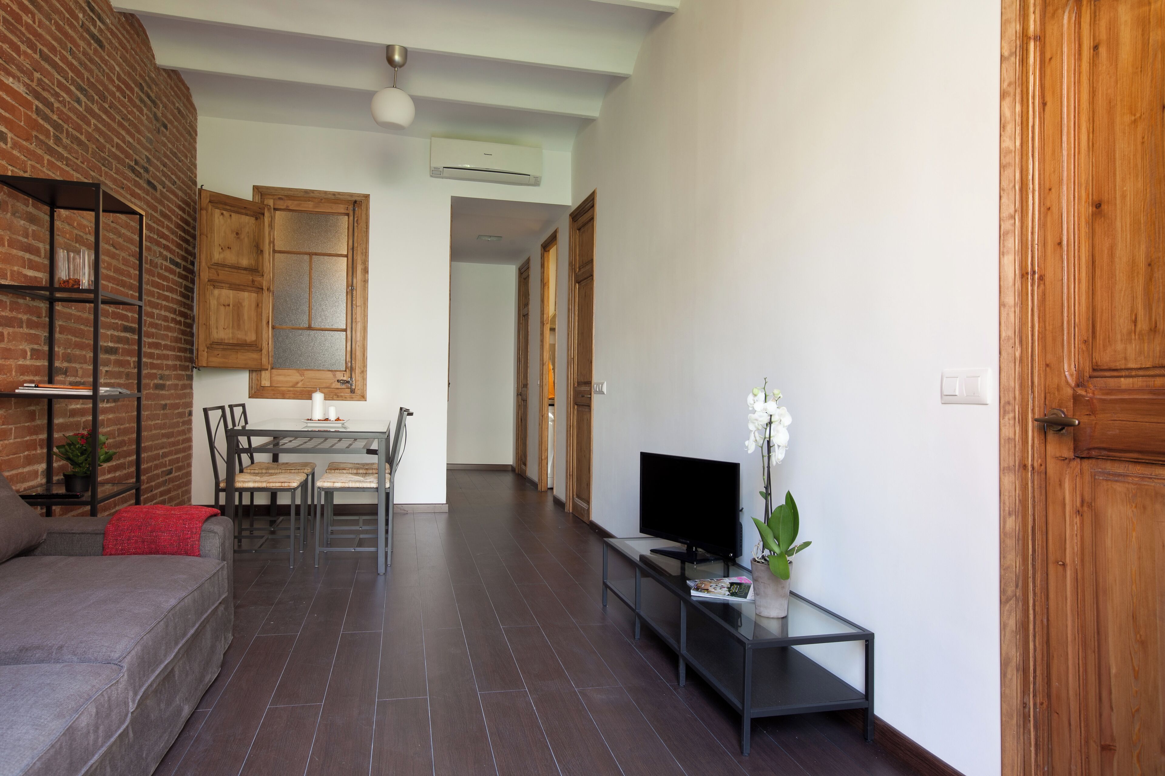 A modern living room with a sofa, TV, and a small table with a plant.