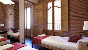 Een kamer met drie bedden, houten kasten en een metselwerk muur.