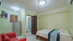 A bedroom with a bed, a red sofa, a refrigerator, and a toilet visible through an open door. - Room-single Room With Queen Bed Near SDQ (Santo Domingo Este)