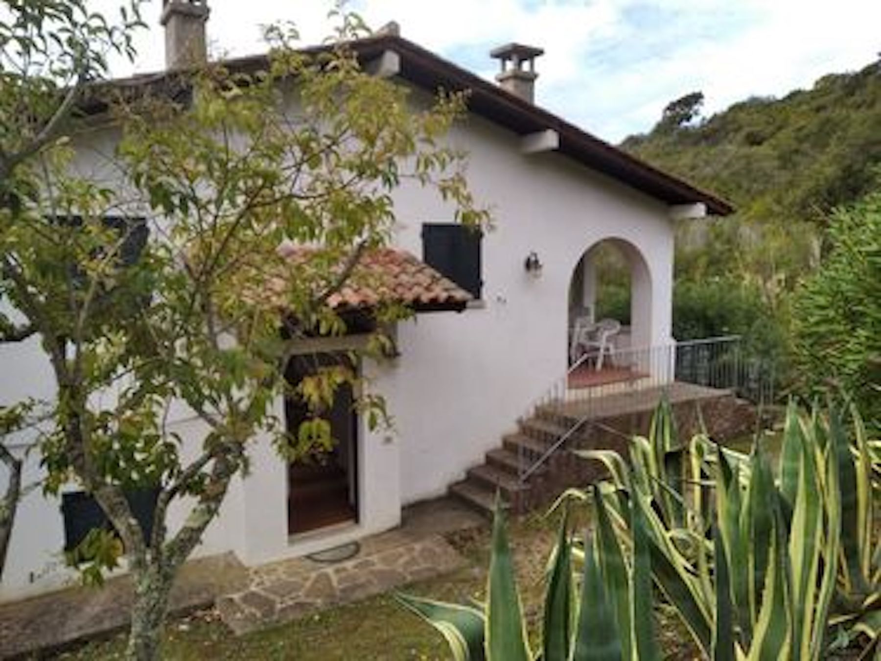 A white building with a stone staircase leading to a porch.